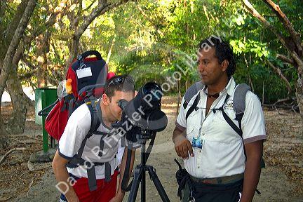 Tourist and nature guide look at wildlife through a telescope in the Manuel Antonio National Park in Puntarenas province, Costa Rica.