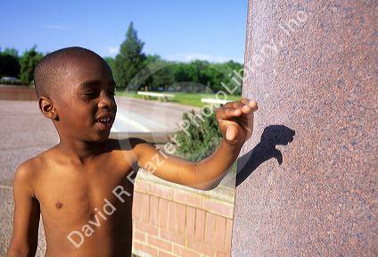 An african american boy makes a shadow puppet on a wall.