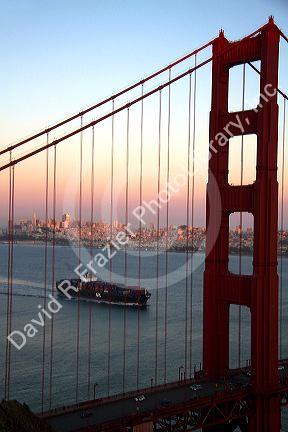 Container ship and the Golden Gate Bridge at dusk in the San Francisco Bay area, California, USA.