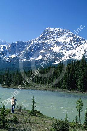 A woman takes a photograph of the Athabasca River and the Canadian Rockies in Jasper National Park, Canada.