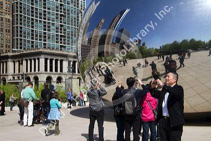 Visitors look at their reflection in the Cloud Gate public sculpture located at the AT&T Plaza in Millennium Park, Chicago, Illinois.