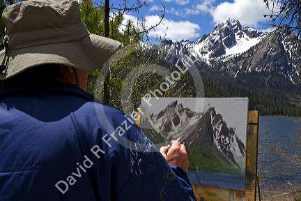 Artist painting McGown Peak and Stanley Lake in the Sawtooth Mountain Range near Stanley, Idaho, USA.