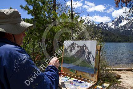 Artist painting McGown Peak and Stanley Lake in the Sawtooth Mountain Range near Stanley, Idaho, USA.