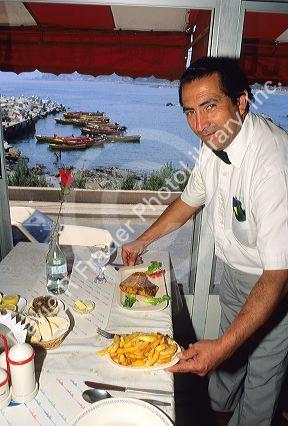 A waiter serves a fish dinner at a restaurant in Chile.