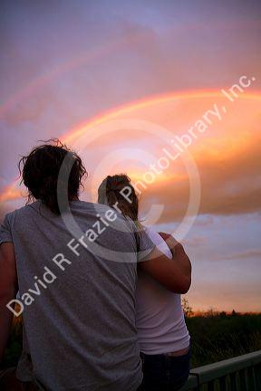 A couple viewing a rainbow at sunset in Boise, Idaho, USA.