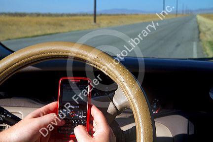 Text messaging on a cell phone while driving in Idaho, USA. MR
