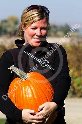 Woman choosing a pumpkin at a pumpkin patch in Fruitland, Idaho, USA. MR
