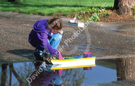 Seven year old girl floating a home made model boat.  MR