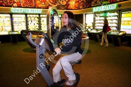 Girl riding a fitness machine in a heath exhibit at the Gulf Coast Exploreum Science Center in Mobile, Alabama, USA.