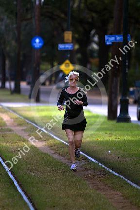 Woman jogging on the St. Charles Streetcar Line in the Garden District of New Orleans, Louisiana, USA.