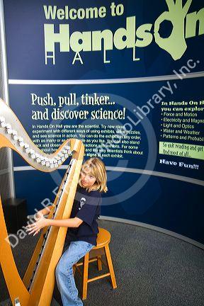 Child playing an electronic stringless harp at the Gulf Coast Exploreum Science Center in Mobile, Alabama, USA.