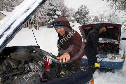 Jump starting a car in winter weather, Boise, Idaho, USA.
