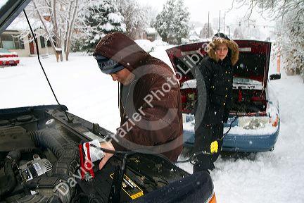 Jump starting a car in winter weather, Boise, Idaho, USA.