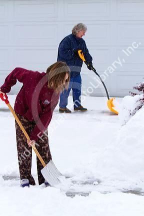 People shovel winter snow off of a driveway in Boise, Idaho, USA.