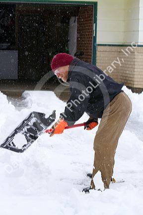 Man shoveling winter snow of off a driveway in Boise, Idaho, USA.