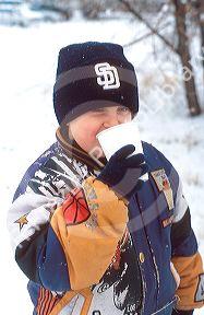 Young boy drinking hot chocolate in the snow.