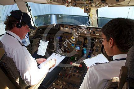 Pilot and first officer reviewing a pre-flight checklist in the cockpit of a Boeing 767 aircraft.