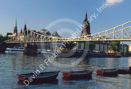 Boats travel under a bridge on the Main River in Frankfurt, Germany.