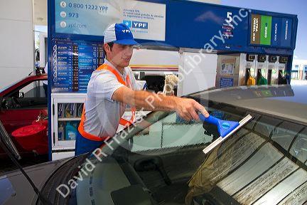 Gas station attendent washing an automobile windshield in Argentina.