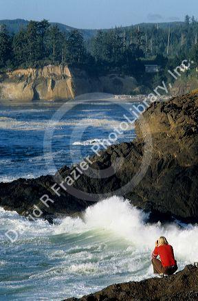A woman watches waves crash on the rocks in Boiler Bay on the Oregon Coast.
