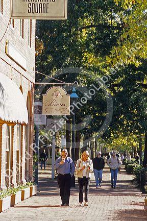 A couple walks along the sidewalk in the commercial area of colonial Williamsburg, Virginia.