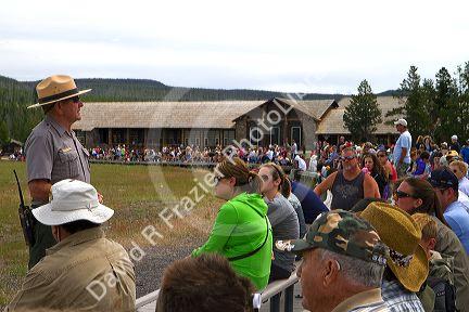 Park ranger giving a tour group information about Old Faithful geyser in Yellowstone National Park, Wyoming, USA.