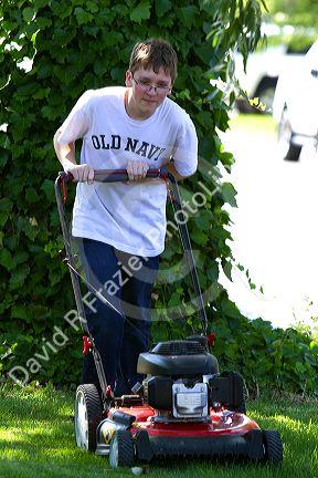 Teenage boy mowing a lawn in Boise, Idaho, USA. MR