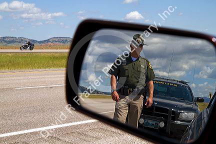 Wyoming Highway Patrol officer on seen in rear-view mirror along I-90 near the Wyoming, South Dakota border, USA. MR