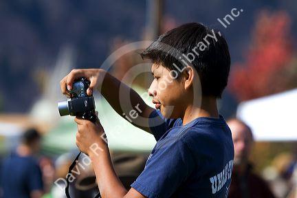 Hispanic boy using a digital camera to capture images of the Trailing of the Sheep Festival in Hailey, Idaho, USA.