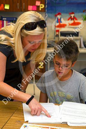 Female teacher helping students in a fourh grade classroom at a public elementary school in Brandon, Florida, USA.
