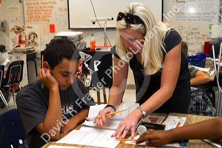 Female teacher helping students in a fourh grade classroom at a public elementary school in Brandon, Florida, USA.