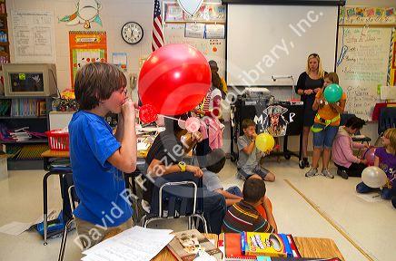 Student blowing up a balloon as part of a science experiment in a fourh grade classroom at a public elementary school in Brandon, Florida, USA.