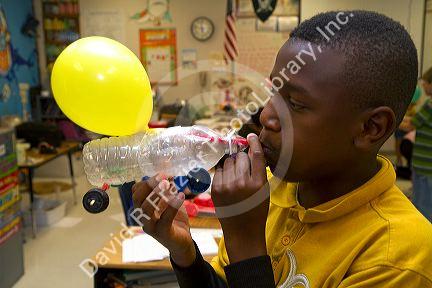 Student blowing up a balloon as part of a science experiment in a fourh grade classroom at a public elementary school in Brandon, Florida, USA.