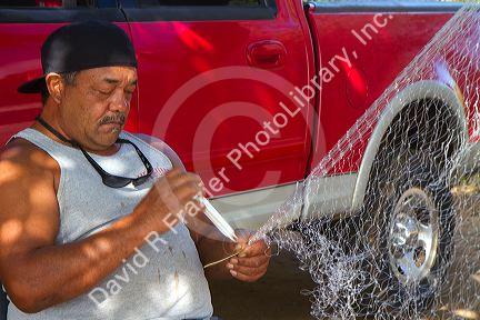 Native hawaiian fisherman mending a net on the island of Kauai, Hawaii, USA. MR