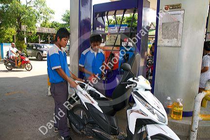Gas station attendent filling up a motor scooter on the island of Ko Samui, Thailand.