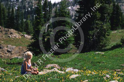 A woman sitting in an Idaho mountain meadow with flowers.