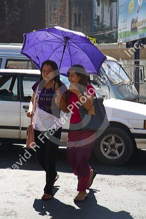 Burmese girls walk together under the shade of an umbrella in (Rangoon) Yangon, (Burma) Myanmar.