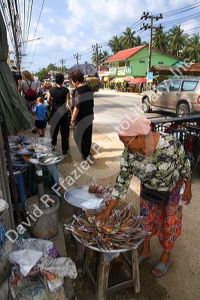 Woman selling dried fish at an open air market on the island of Ko Samui, Thailand.