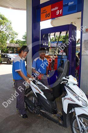 Gas station attendent filling up a motor scooter on the island of Ko Samui, Thailand.