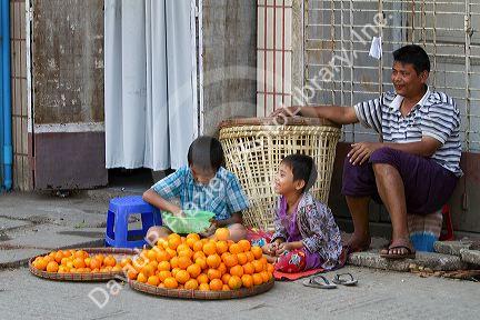 Burmese father and sons selling oranges on the street in (Rangoon) Yangon, (Burma) Myanmar.