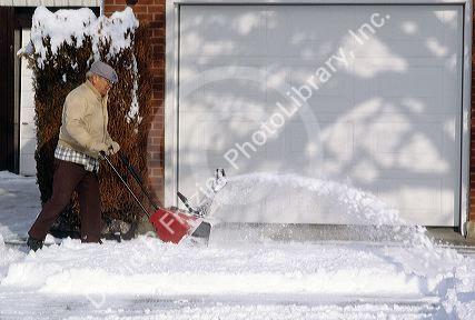 A man clearing snow from his driveway with snowblower.
