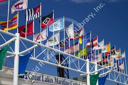 Shipping company flags in front of the Great Lakes Maritime Center along the St. Clair river where it meets the Black River at Port Huron, Michigan, USA.
