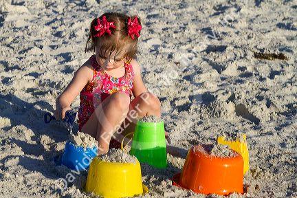 Three year old girl playing in the sand at a beach on the gulf coast of Florida, USA.
