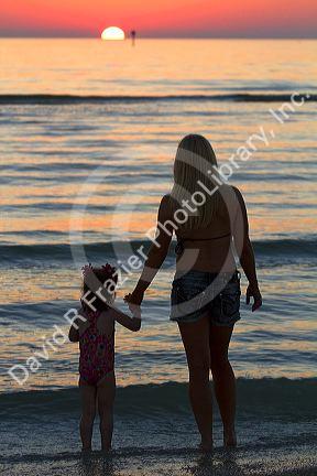 Mother and daughter holding hands at sunset at the beach on the  gulf coast of Florida, USA. MR