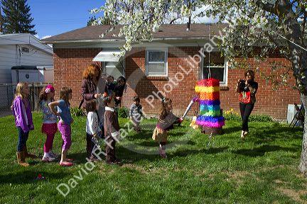 Children hitting a pinata at a hispanic childs birthday party in Boise, Idaho, USA.