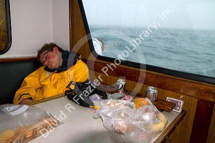Teenage boy taking a nap on a chartered fishing boat in the pacific ocean near Newport, Oregon, USA.