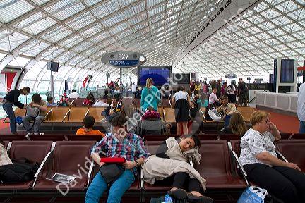 Travelers in a waiting room at Charles de Gaulle Airport, Paris, France.