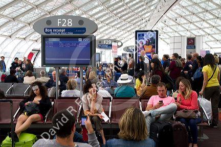 Travelers in a waiting room at Charles de Gaulle Airport, Paris, France.