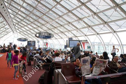 Travelers in a waiting room at Charles de Gaulle Airport, Paris, France.