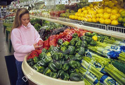 A young girl shopping for fruits and vegetables in a supermarket.
